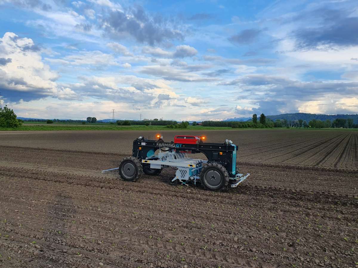 Das Bild zeigt eine landwirtschaftliche Maschine bei der Arbeit auf einem Feld. 